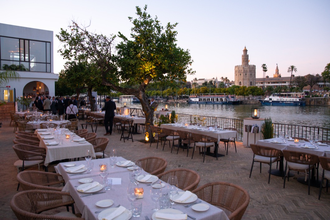 Cena institucional de FESTELCO'26 en la terraza del Restaurante Río Grande junto al Guadalquivir, con la Torre del Oro al fondo